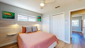 A bedroom with a bed, a ceiling fan, a window, and a door.