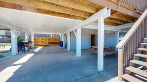 Un espace extérieur abrité, équipé de tables de pique-nique et d’un barbecue.