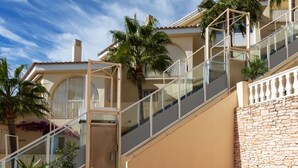 Un immeuble résidentiel à plusieurs étages, doté d’un mur en pierre et d’un escalier en verre.