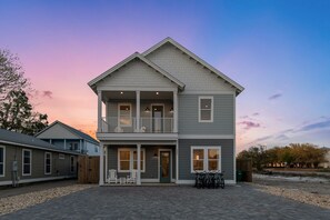 Une maison à deux étages avec un balcon, un porche à l’avant et une allée.