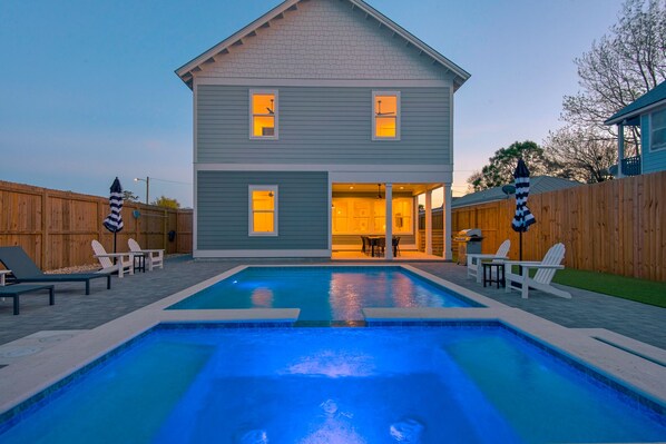 A two-story house with a swimming pool, outdoor seating, and a covered patio area.