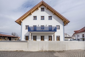 A two-story building with a balcony, multiple windows, and a red roof.