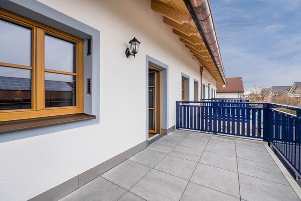 A building with a balcony, a blue fence, and a door.