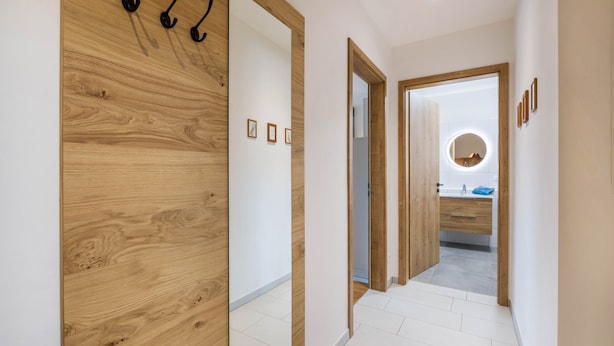 Ein Flur mit Holzwandverkleidung, einem Spiegel und einem durchgegangenen Tür zu sichtbarem Badezimmer.