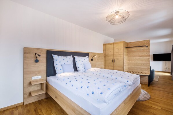 Una camera da letto moderna con un letto con struttura in legno, una TV integrata e un armadio.