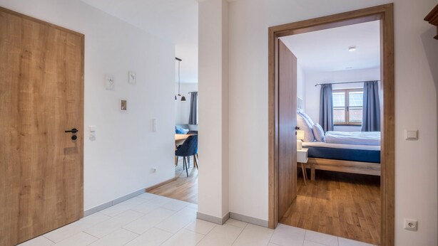 Un pasillo que conduce a un dormitorio con cama, escritorio y silla.