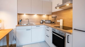 Una cocina moderna con armarios blancos, encimera de madera, horno empotrado y microondas.