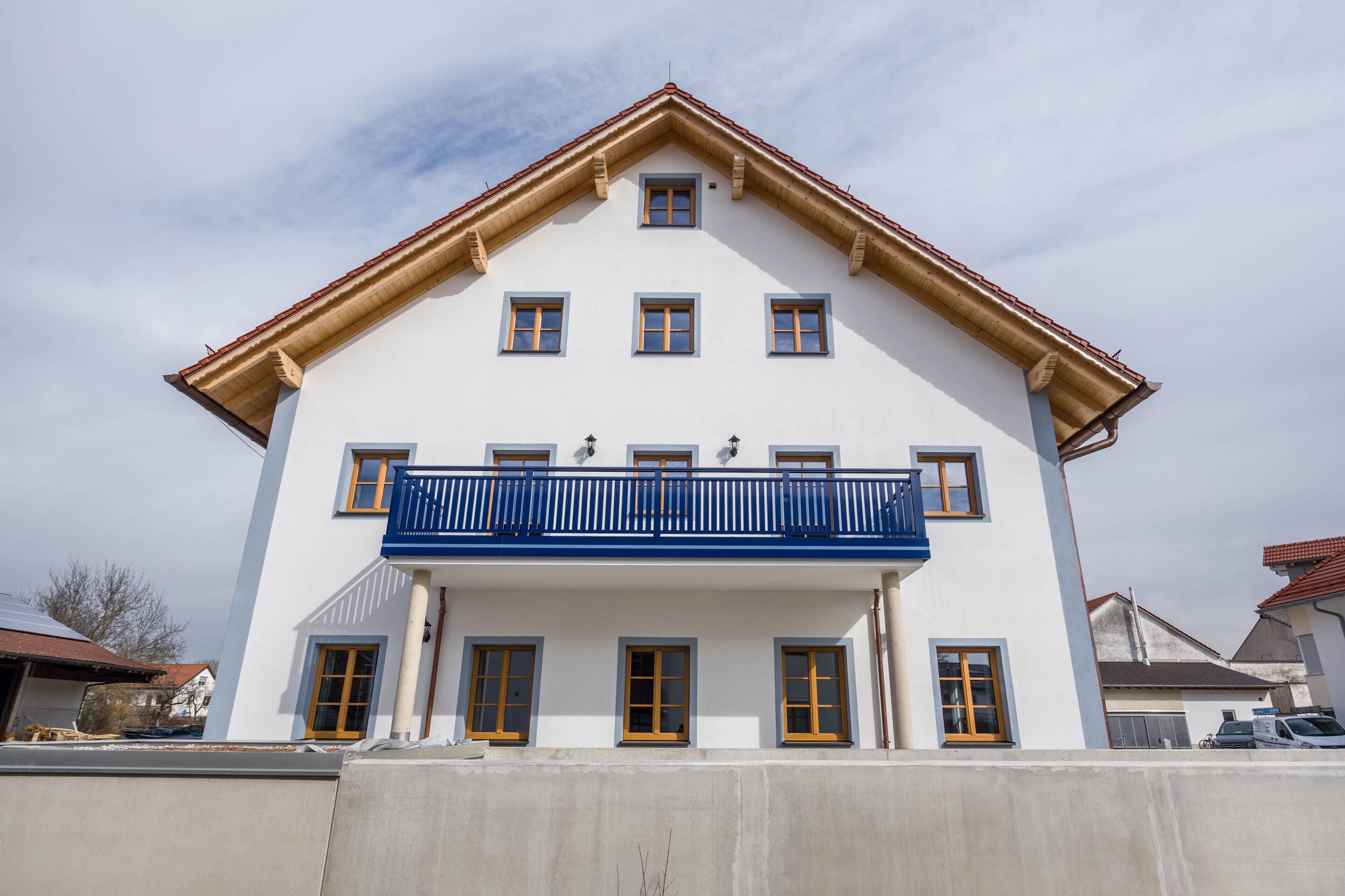 A two-story building with a balcony, multiple windows, and a visible garage.