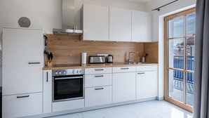 Eine moderne Küche mit weißen Schränken, einer Holz Arbeitsplatte, einem Einbauofen und einem großen Fenster mit Aussicht.