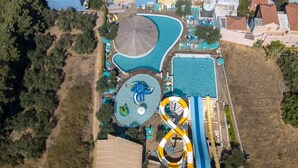 An aerial view of a residential area with multiple swimming pools, a water slide, and a beach area. - Iolida Village Hotel (Chania)