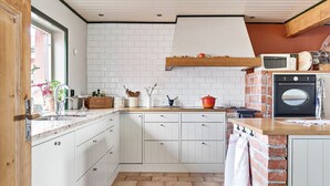 A kitchen with white cabinets, a brick backsplash, and a wooden countertop. - Fantastic Villa in the Countryside - 20 Mins From Malmo (Svedala)