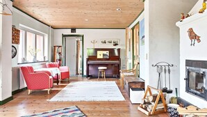 A cozy living room with a wooden ceiling, a fireplace, and a piano. - Fantastic Villa in the Countryside - 20 Mins From Malmo (Svedala)