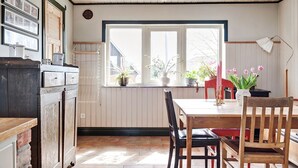 A dining area with a wooden table and chairs, a window with potted plants, and a view of the outside. - Fantastic Villa in the Countryside - 20 Mins From Malmo (Svedala)
