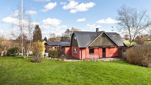 A red barn with a metal roof and a large chimney, surrounded by green grass and trees. - Fantastic Villa in the Countryside - 20 Mins From Malmo (Svedala)