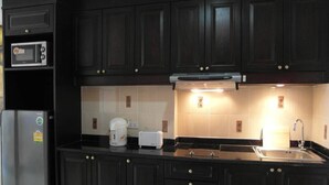 Una cocina con armarios de madera oscura, un refrigerador de acero inoxidable, un microondas, un tostador y un fregadero.