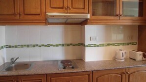 Uma cozinha com armários de madeira, uma pia de aço inoxidável, um fogão embutido e uma torradeira.