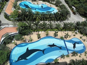 A swimming pool with dolphin murals, surrounded by palm trees and a beach area. - View Talay Vt1b F4 R193 - Fully Equiped Apartment Suite (Pattaya)