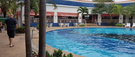 A swimming pool with lounge chairs and a restaurant named "Peter & Peter Restaurant" in the background.