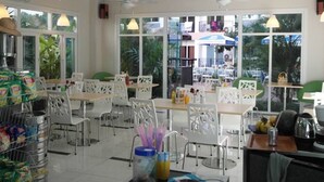 A restaurant with white chairs and tables, large windows, and ceiling fans. - Plaza Residence F6 R62 Residence (Pattaya)