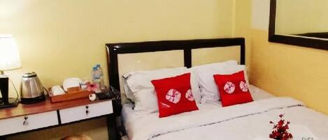 Una habitación de hotel con una cama, una mesita de noche, una lámpara y un espejo en la pared.