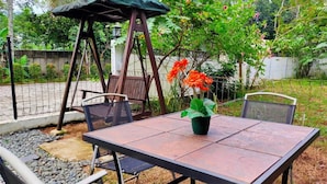 A patio with a table and chairs, a swing set, and a potted plant. - Bakom Inn Syariah - Standard Double Room (Bogor)