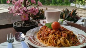 A dining table with a plate of spaghetti, a cup, and a small potted plant. - Comfortable Room With Ac and Wifi for 2 People (Bogor)