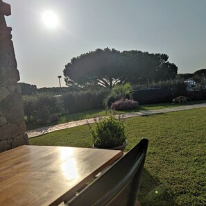 Une terrasse avec un mur en pierre, une table et une chaise.