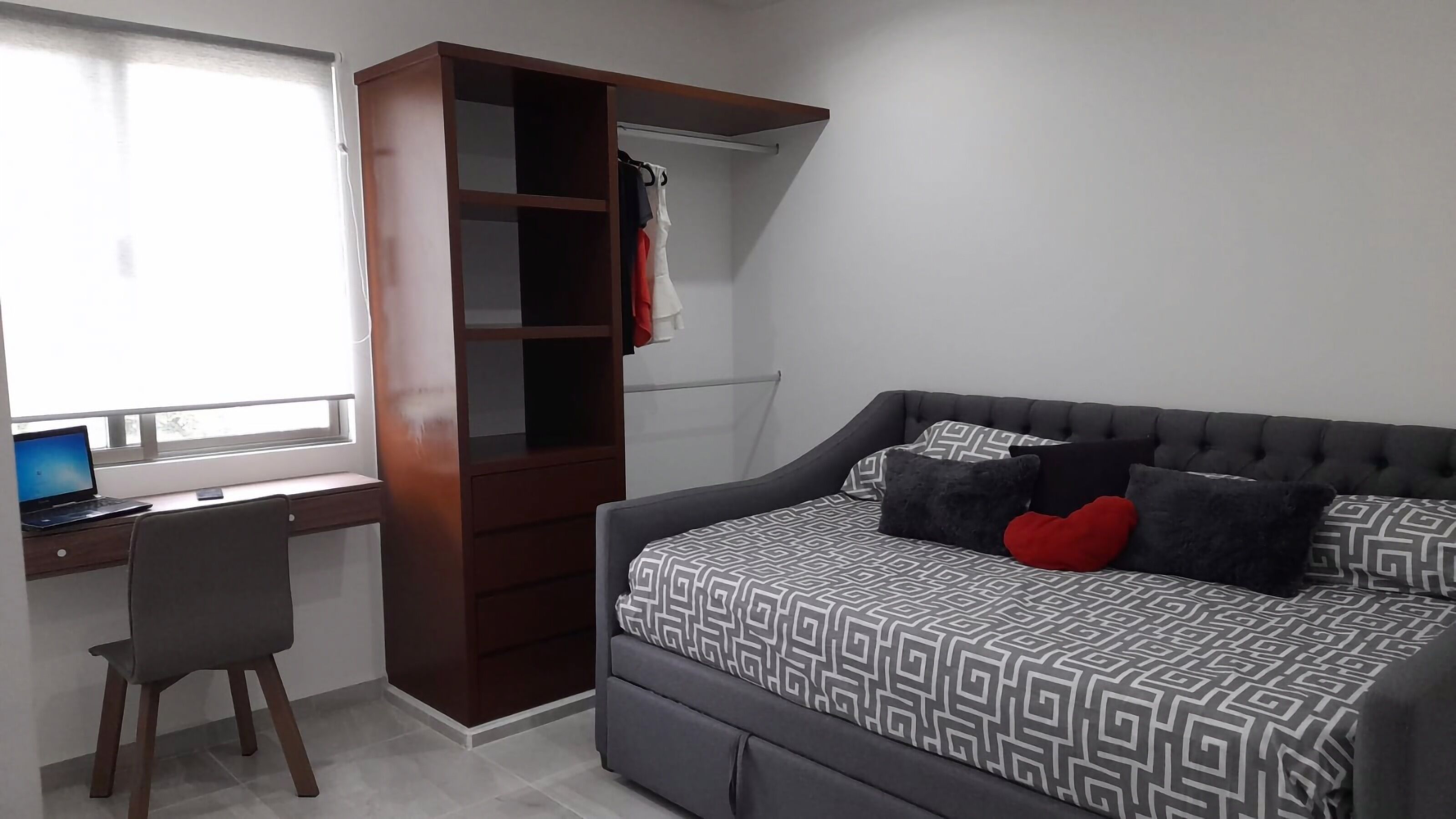 Un dormitorio con cama, escritorio y armario.