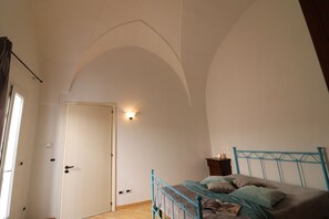 A bedroom with a bed, a door, and a light fixture.