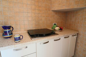 A kitchen with a stove, a coffee maker, and a bowl of fruit.