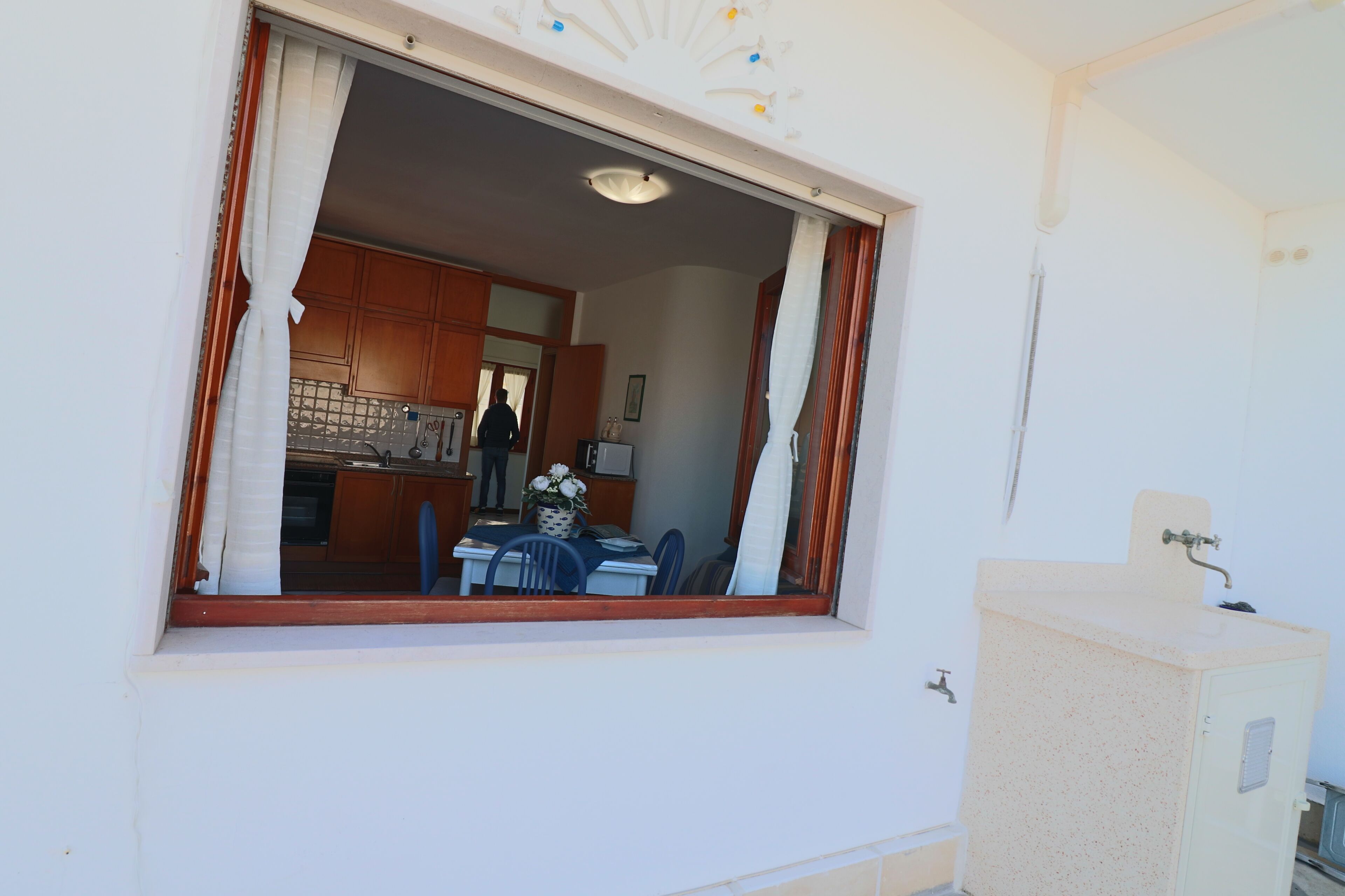 Una habitación con ventana, lavamanos y armario.