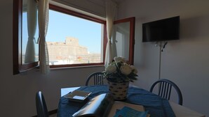 A room with a dining table, chairs, a potted plant, a book, and a TV mounted on the wall. - Casa Sophia Panoramic Terrace and Elegant Stay in the Heart of Otranto (Otranto)