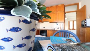 A kitchen with wooden cabinets, a microwave, and a potted plant on the counter. - Casa Sophia Panoramic Terrace and Elegant Stay in the Heart of Otranto (Otranto)