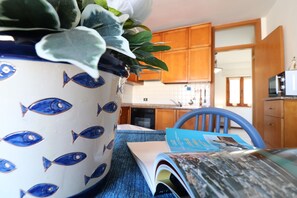 Cozinha com armários de madeira, micro-ondas e uma planta em vaso sobre o balcão.