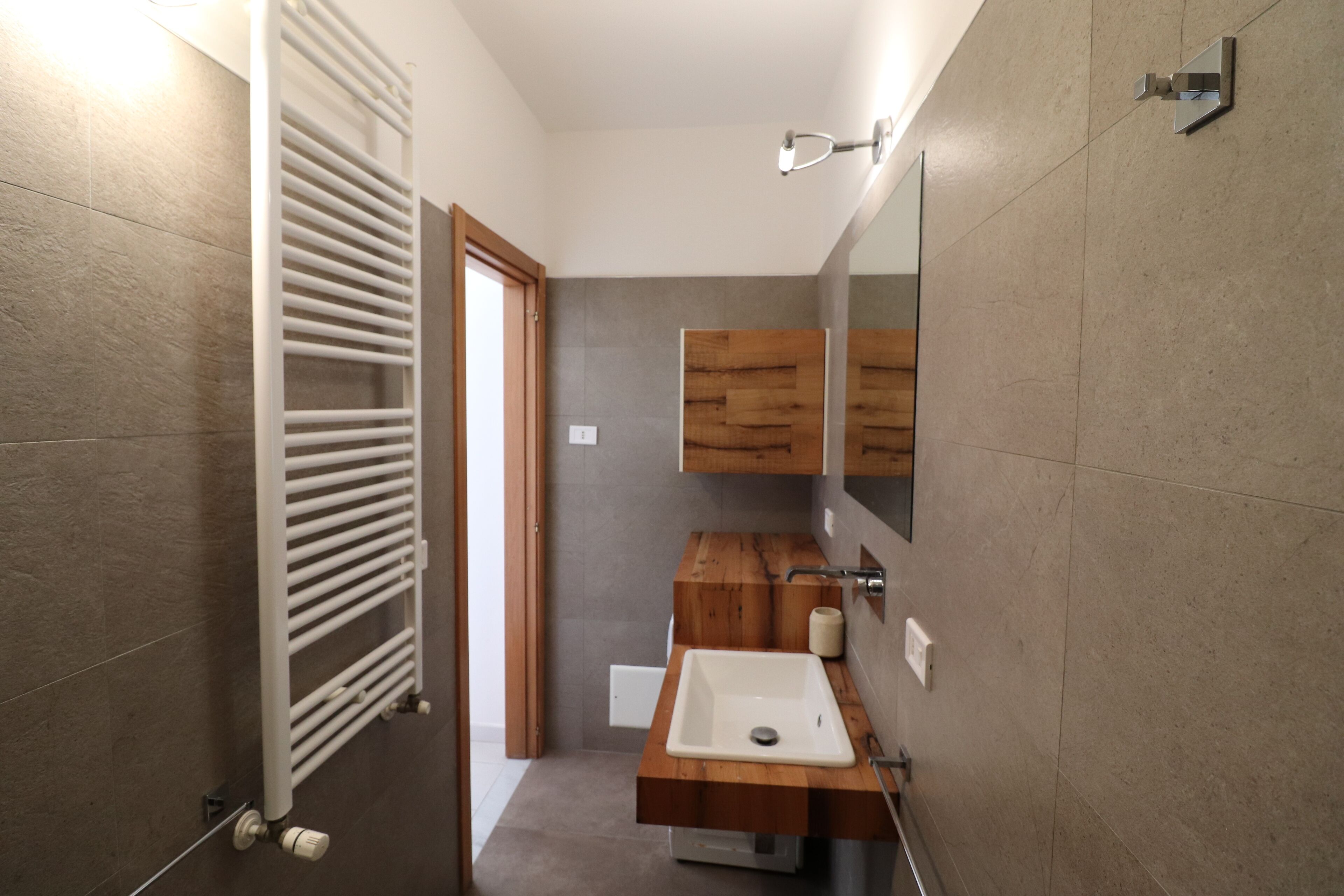 A modern bathroom with a built-in sink, wooden vanity, and a towel rack.