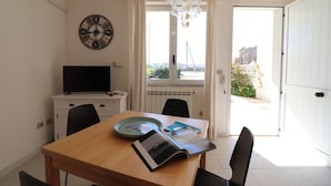 Ein Essbereich mit Holztisch, Stühlen, einem Fernseher und Blick ins Freie.