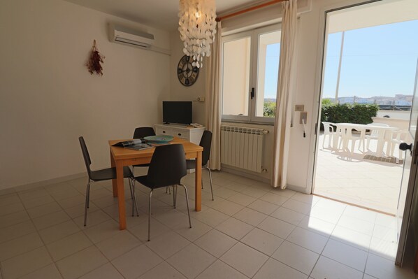 Un'area pranzo con tavolo e sedie, una televisione e vista sull'esterno tramite una porta vetrata.