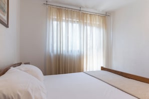 A hotel room with a bed, curtains, and a wall-mounted picture.