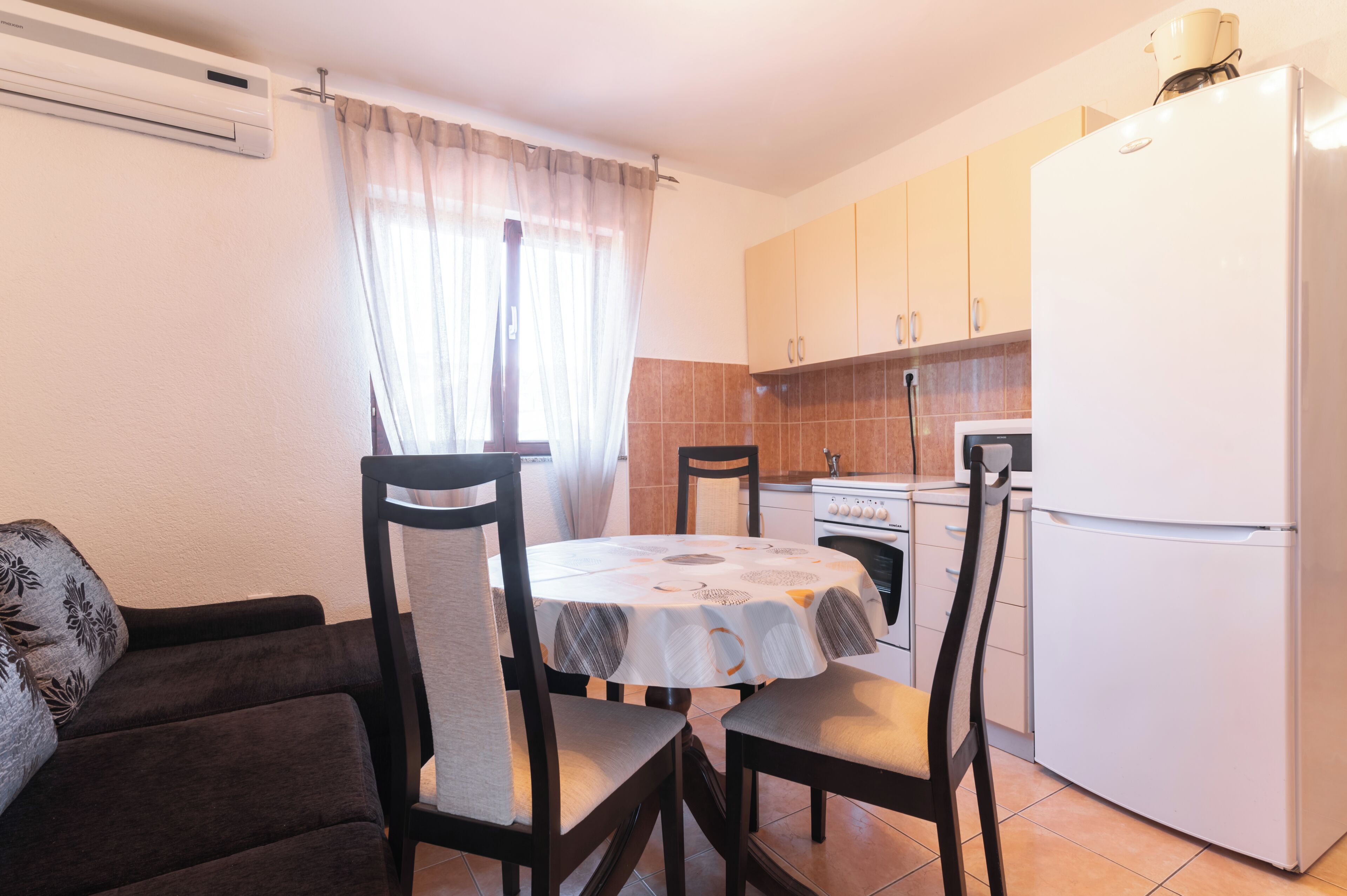 Uma cozinha compacta com mesa, cadeiras, geladeira e fogão.