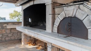 Une cheminée extérieure en pierre, dotée d’une cheminée, ainsi qu’un banc et un mur en pierre.
