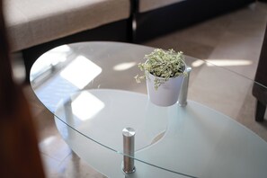 A glass-top table with a potted plant, a metal stand, and a cushioned bench in the background. - Beachfront Studio-apartment Spazzio (Preko)