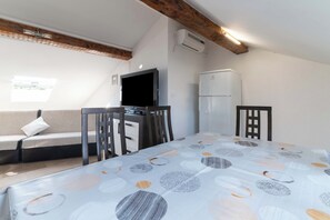 A room with a bed, a TV, a refrigerator, a sofa, and a window. - Beachfront Studio-apartment Spazzio (Preko)