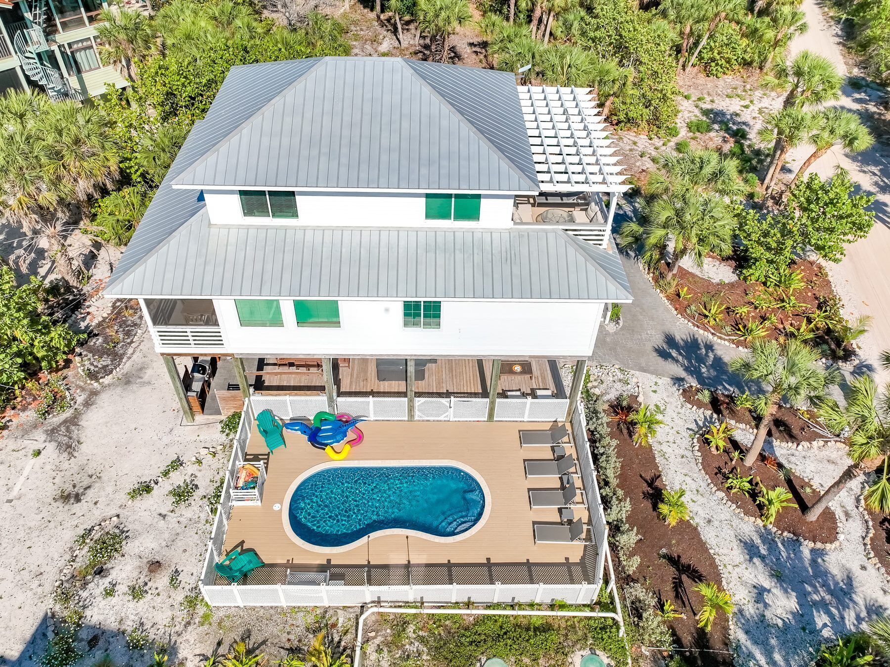 A two-story house with a pool, surrounded by tropical vegetation.