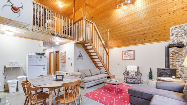 Ein gemütliches Interieur mit einer Holztreppe, einer Essecke, einer Couch und einem Kamin.