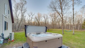 Ein Whirlpool in einem Garten mit einem Haus und Bäumen im Hintergrund.