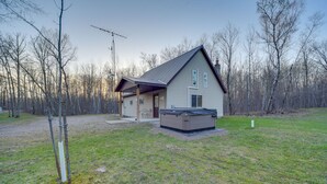 Ein einstöckiges Haus mit überdachter Veranda, einer kleinen angebauten Garage und einem Whirlpool im Garten.