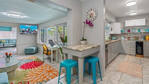 A modern kitchen with white cabinets, a blue countertop, and a kitchen island with stools.