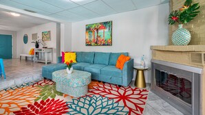 A living room with a blue sofa, colorful cushions, a round coffee table, and a fireplace.