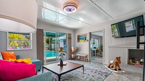 A spacious living area with a pool view, a television, and a giraffe decoration.