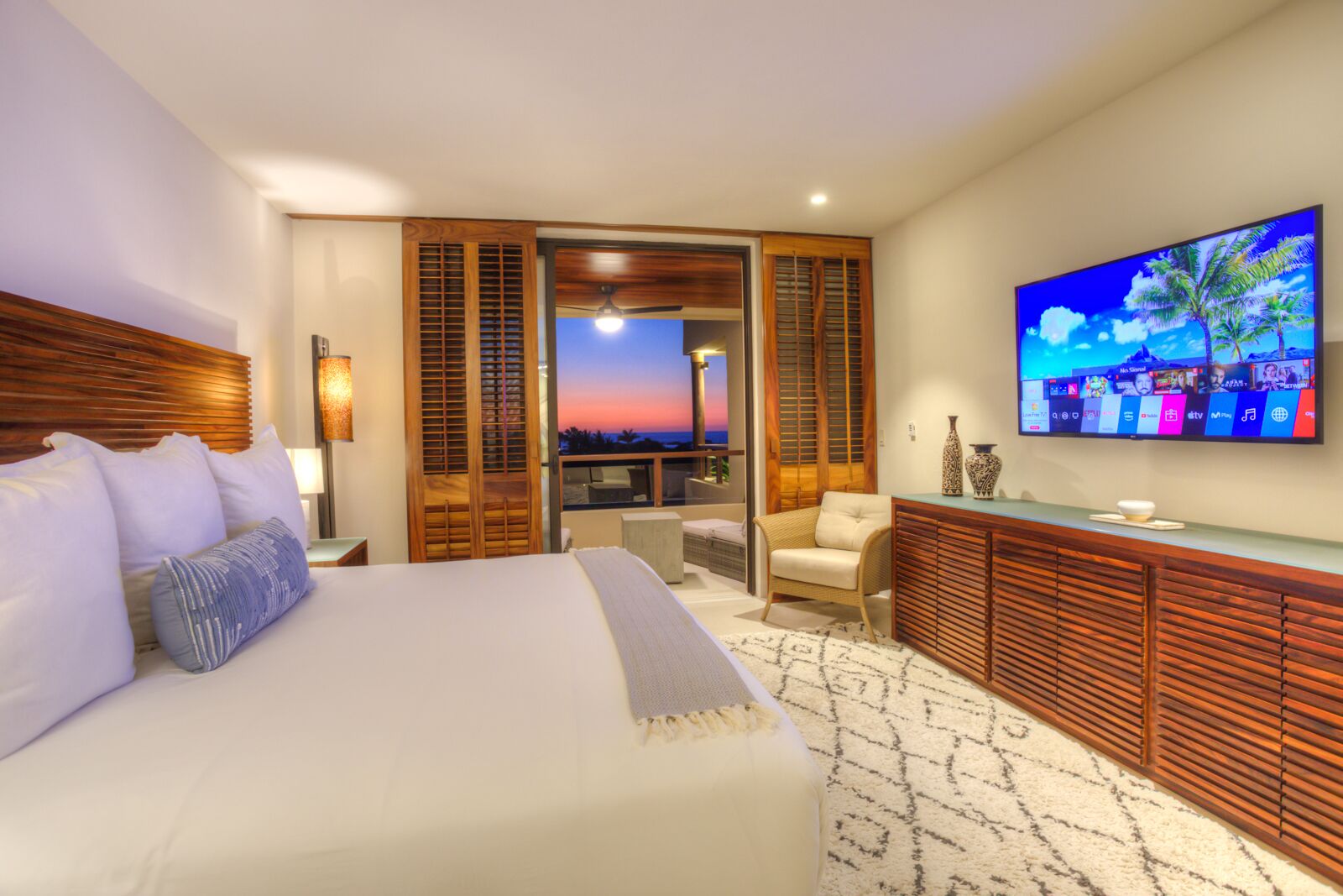 A hotel room with a bed, a seating area with a view, and a TV on the wall.